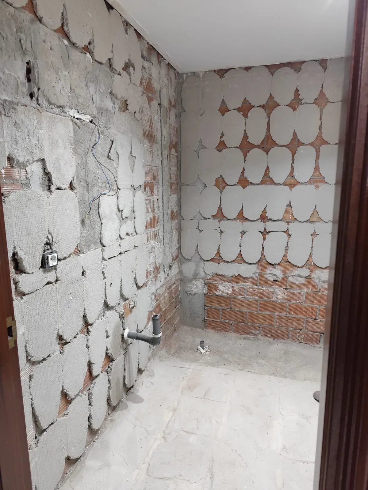 Baño durante la demolición, con las paredes picadas a ladrillo
