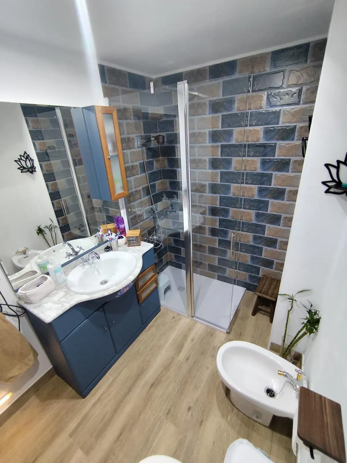 Baño reformado con azulejo tipo ladrillo, mueble azul y ducha